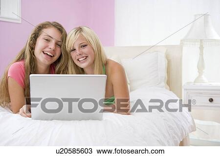 Teenage Girls Lying On Bed Using Laptop View Large Photo Image Stock Image - Teenage Girls Lying On Bed Using Laptop. Fotosearch