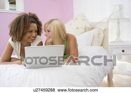 Stock Photo - Teenage Girls Lying On Bed Using Laptop . Fotosearch