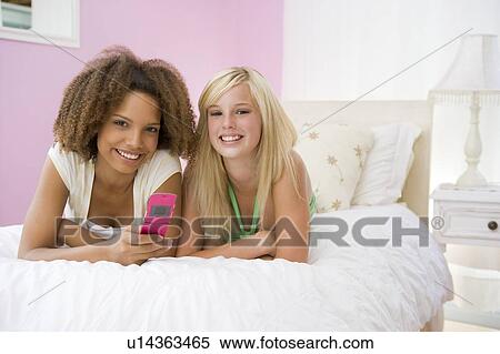 Teenage Girls Lying On Bed Using Cellphone View Large Photo Image Stock Photography - Teenage Girls Lying On Bed Using Cellphone . Fotosearch
