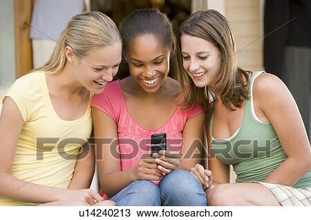 Teenage Girls Sitting Outside Playing With Mobile Phone View Large Photo Image Stock Image - Teenage Girls Sitting Outside Playing With Mobile Phone. Fotosearch