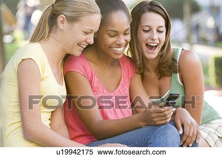Teenage Girls Sitting Outside Playing With Mobile Phone View Large Photo Image Stock Photography - Teenage Girls Sitting Outside Playing With Mobile Phone. Fotosearch