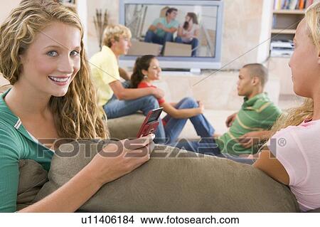 Picture - Teenagers Hanging Out In Front Of Television Using Mobile Phones . Fotosearch