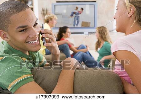 Stock Photo - Teenagers Hanging Out In Front Of Television Using Mobile Phones . Fotosearch