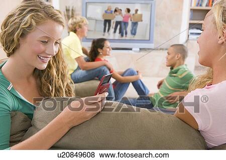 Stock Photo - Teenagers Hanging Out In Front Of Television Using Mobile Phones . Fotosearch
