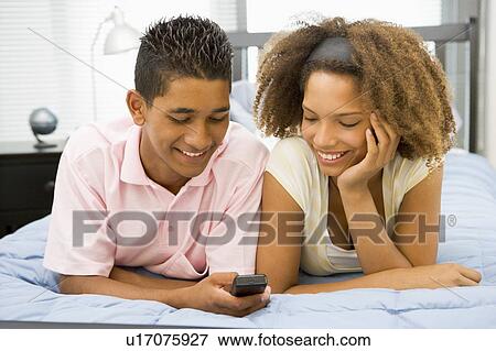 Teenagers Lying On Bed Together Looking At Mobile Phone View Large Photo Image Stock Photo - Teenagers Lying On Bed Together Looking At Mobile Phone. Fotosearch