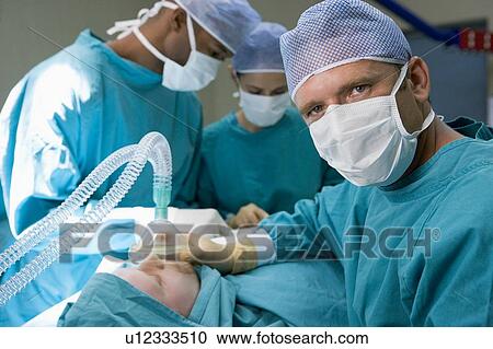 Stock Image - Three Surgeons Operating On A Patient. Fotosearch