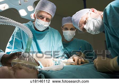 Stock Image - Three Surgeons Operating On A Patient. Fotosearch