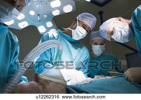 Stock Photograph - Three Surgeons Operating On A Patient. Fotosearch