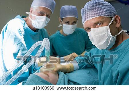 Stock Photograph - Three Surgeons Operating On A Patient. Fotosearch