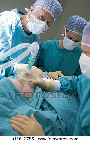 Stock Photography - Three Surgeons Operating On A Patient. Fotosearch
