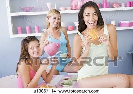 Three young woman sitting at a table having tea and a snack View Large Photo Image Picture - Three young woman sitting at a table having tea and a snack. Fotosearch