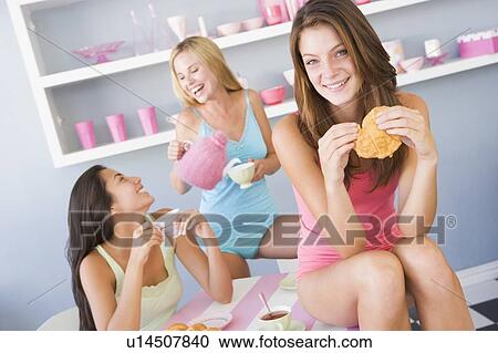 Three young woman sitting at a table having tea and a snack View Large Photo Image Stock Image - Three young woman sitting at a table having tea and a snack. Fotosearch