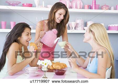 Three young woman sitting at a table having tea and a snack View Large Photo Image Stock Photo - Three young woman sitting at a table having tea and a snack. Fotosearch