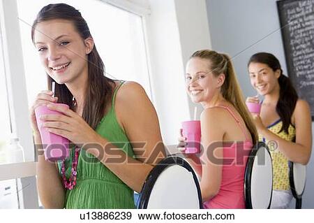 Stock Photo - Three young women having a cold drink in a cafeteria. Fotosearch
