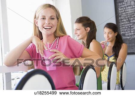 Stock Photo - Three young women having a cold drink in a cafeteria. Fotosearch