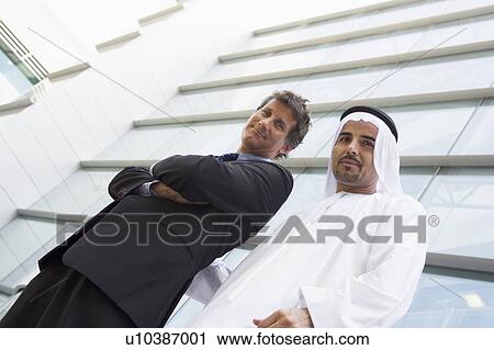 Two businessman standing outdoors by building smiling (high key/selective focus) View Large Photo Image Stock Image - Two businessman standing outdoors by building smiling (high key/selective focus). Fotosearch