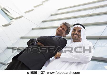 Two businessmen standing outdoors by building (high key/selective focus) View Large Photo Image Stock Photo - Two businessmen standing outdoors by building (high key/selective focus). Fotosearch