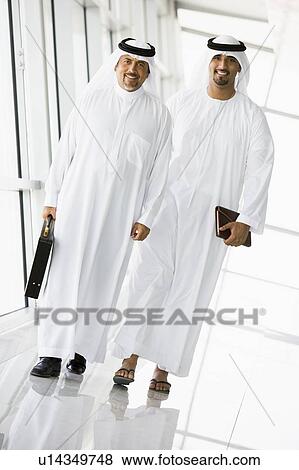 Two businessmen walking in a corridor smiling (high key/selective focus) View Large Photo Image Stock Photo - Two businessmen walking in a corridor smiling (high key/selective focus). Fotosearch