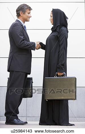Two businesspeople outdoors shaking hands and smiling View Large Photo Image Stock Image - Two businesspeople outdoors shaking hands and smiling. Fotosearch