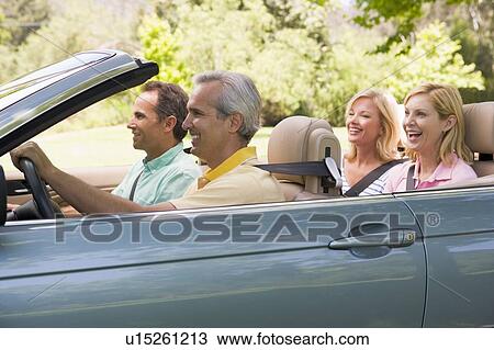 Stock Image - Two couples in convertible car smiling. Fotosearch