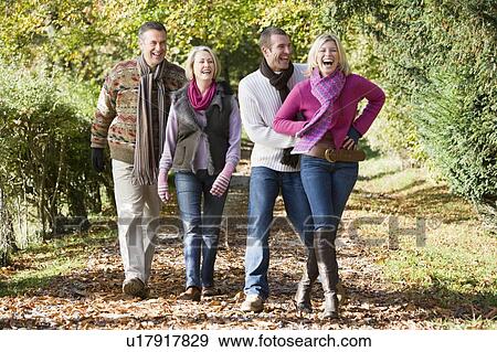 Stock Photo - Two couples walking on path outdoors smiling (selective focus). Fotosearch