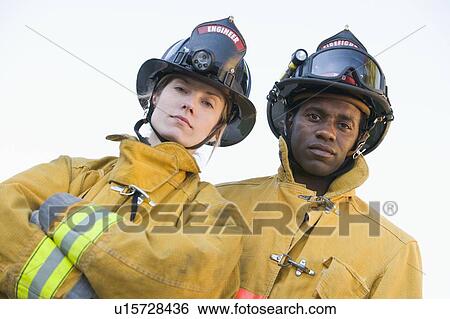 Two firefighters standing outdoors wearing helmets View Large Photo Image Stock Photograph - Two firefighters standing outdoors wearing helmets. Fotosearch