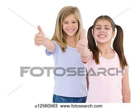 Stock Image - Two girl friends giving thumbs up smiling. Fotosearch