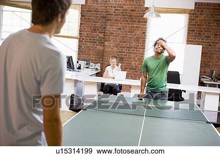 Stock Photo - Two men in office space playing ping pong. Fotosearch