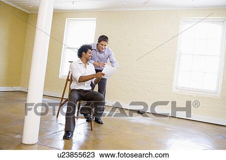 Two men with ladder in empty space looking at paper View Large Photo Image Stock Image - Two men with ladder in empty space looking at paper. Fotosearch