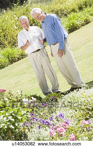 Stock Image - Two senior men in a flower garden. Fotosearch