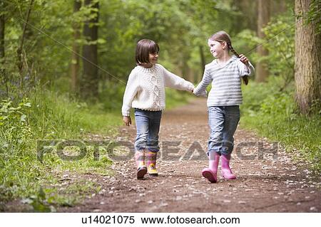 Two sisters walking on path holding hands smiling View Large Photo Image Stock Photography - Two sisters walking on path holding hands smiling. Fotosearch
