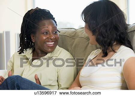 Stock Photo - Two women talking in living room and smiling. Fotosearch