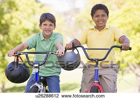 Two young boys on bicycles outdoors smiling View Large Photo Image Stock Image - Two young boys on bicycles outdoors smiling. Fotosearch
