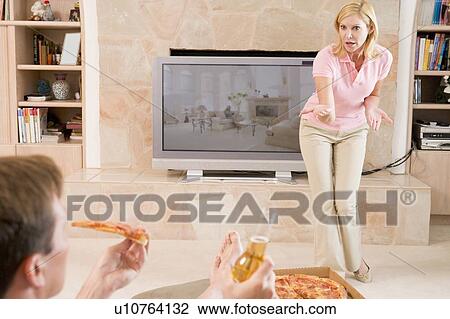 Stock Image - Wife Telling Husband Off For Drinking Beer And Eating Pizza. Fotosearch