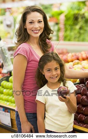Woman and daughter shopping for apples at a grocery store View Large Photo Image Picture - Woman and daughter shopping for apples at a grocery store. Fotosearch