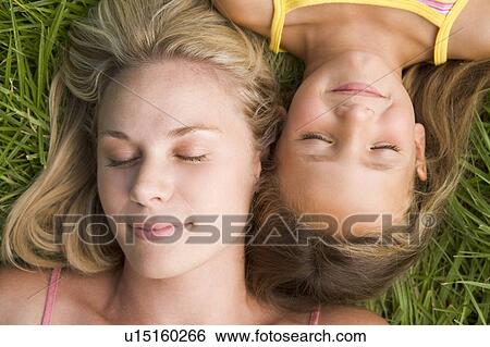 Stock Photograph - Woman and young girl lying in grass sleeping. Fotosearch
