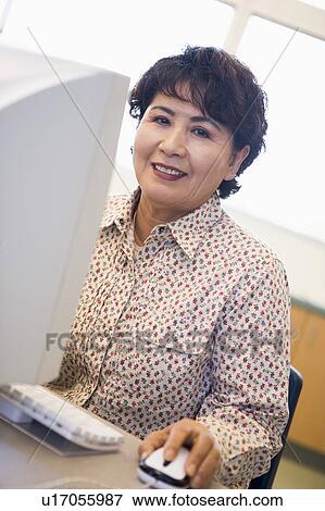 Stock Photo - Woman at computer smiling and looking at monitor (high key). Fotosearch