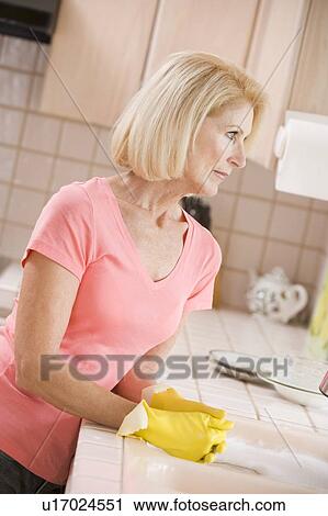 Stock Image - Woman Cleaning Kitchen Counter. Fotosearch