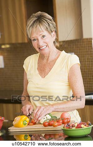 Stock Image - Woman Cutting Up Vegetables. Fotosearch