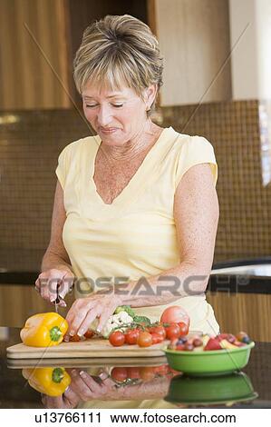Stock Image - Woman Cutting Up Vegetables. Fotosearch