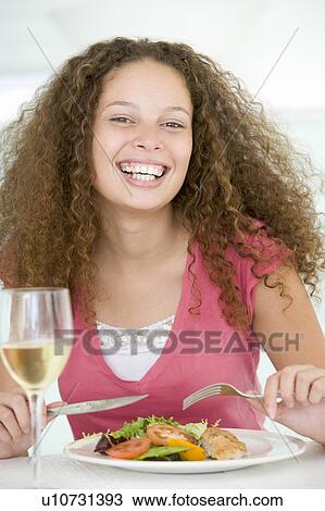 Stock Image - Woman Eating meal, mealtime With A Glass Of Wine . Fotosearch