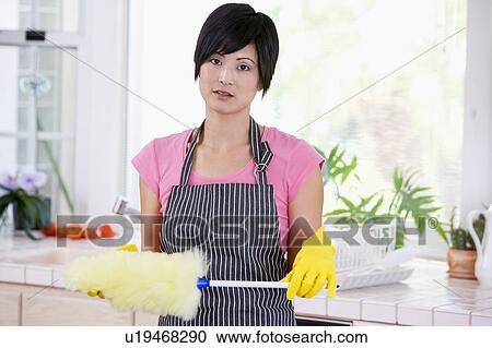 Stock Image - Woman Holding Duster And Wearing Rubber Gloves Not Looking Impressed. Fotosearch