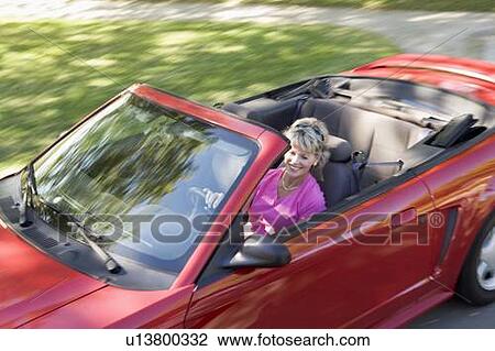 Stock Image - Woman in convertible car smiling. Fotosearch