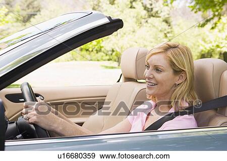 Stock Photo - Woman in convertible car smiling. Fotosearch
