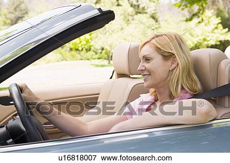 Stock Photo - Woman in convertible car smiling. Fotosearch