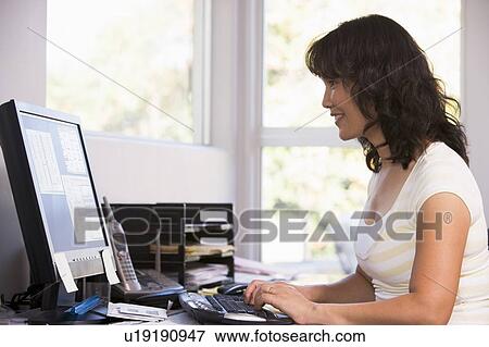 Woman in home office using computer and smiling View Large Photo Image Stock Photo - Woman in home office using computer and smiling. Fotosearch