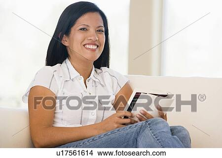 Picture - Woman in living room reading book smiling. Fotosearch