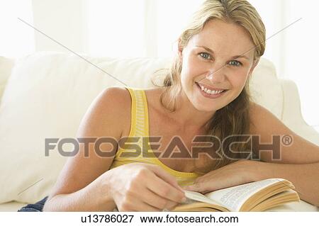 Woman in living room reading book smiling View Large Photo Image Stock Photo - Woman in living room reading book smiling. Fotosearch