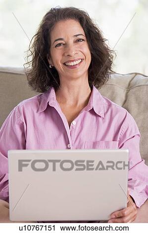 Woman in living room with laptop smiling View Large Photo Image Stock Image - Woman in living room with laptop smiling. Fotosearch