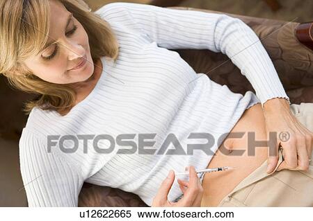 Stock Photography - Woman injecting drugs to prepare for IVF treatment. Fotosearch